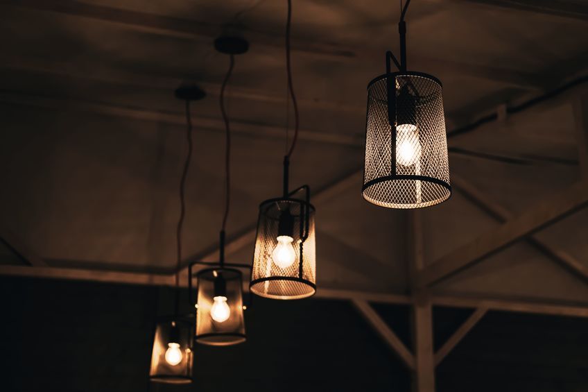 group of lamps in mesh metal shades against the background of rough wooden ceiling. blurred loft interior.