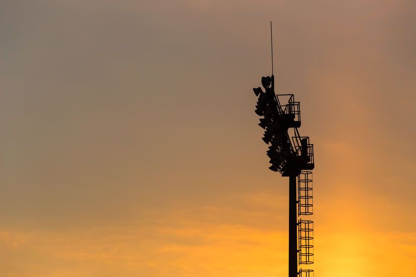 Mast lighting mantles at the stadium on a sunset background.